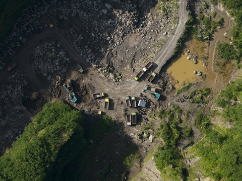Aerial view of Tambang Pasir Merapi Kali Gendol Sand Mine with excavators and dump trucks operating on the rocky terrain Kecamatan Cangkringan, Daerah Istimewa Yogya, Indonesia.