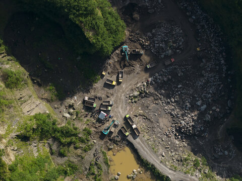 Aerial view of Tambang Pasir Merapi Kali Gendol Sand Mine with excavators and dump trucks operating on rocky terrain Kecamatan Cangkringan, Daerah Istimewa Yogya, Indonesia.
