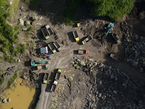 Aerial view of Tambang Pasir Merapi Kali Gendol Sand Mine with trucks and excavators operating on the rocky terrain Kecamatan Cangkringan, Daerah Istimewa Yogya, Indonesia.