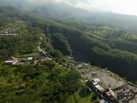 Aerial view of Tambang Pasir Merapi Kali Gendol Sand Mine surrounded by lush tropical forests and a deep valley in Kecamatan Cangkringan, Daerah Istimewa Yogya, Indonesia.