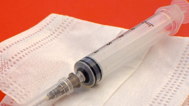 Syringe and white mask, symbols of care and prevention in a clean and impactful composition. 