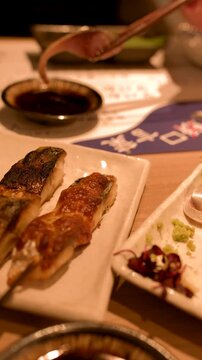 Chopsticks Dipping Fresh Mackerel Sashimi into Soy Sauce at Japanese Restaurant