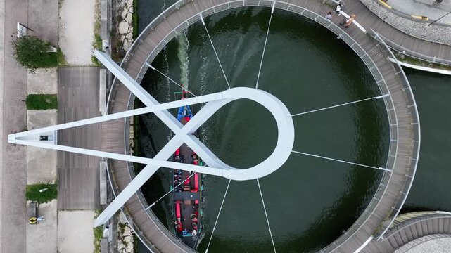 Aerial view of Circular Pedestrian Bridge with a traditional boat passing underneath in Aveiro, Aveiro, Portugal.