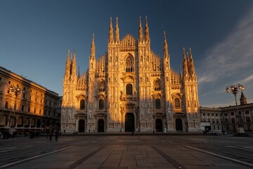 Naklejka premium Grand Gothic Cathedral Illuminated by Golden Hour Sunlight in European City Square