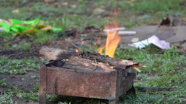 Small Outdoor Fire Burning on Rusted Metal Box with Dry Wood in Open Ground