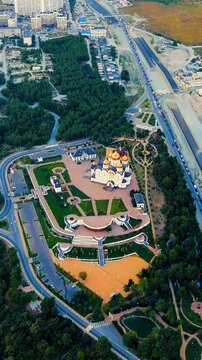 Vertical video. Gelendzhik, Russia. Cathedral of St. Andrew the First-Called, white-stone Vladimir-Suzdal style with gilded domes, Drone footage over Andreevsky park and the M4 highway. Drone footage