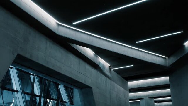 Concrete walls and geometric lines create an abstract pattern in a modern architectural interior, illuminated by linear neon lights, evoking a futuristic and industrial design