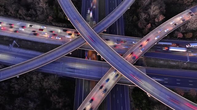 An overhead drone Timelapse of heavy traffic on an intersection with cars flying by at night with their headlights on