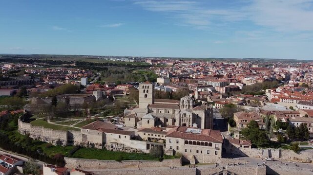 Spectacular 4K aerial drone overflight advancing towards the Romanesque Cathedral and medieval castle ruins in Zamora, Spain. High-angle view of the old town and modern city on a sunny day