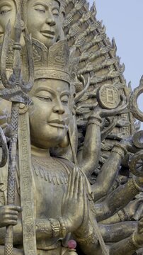 Detailed close-up of a massive multi-armed Buddhist-style statue at a Vietnamese cultural attraction during daytime.