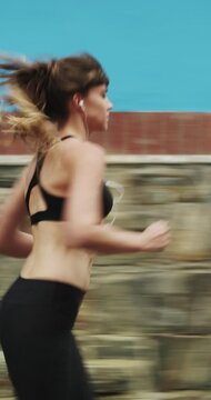 Running, earphones and speed with woman in city for streaming service, workout playlist and fitness. Runner podcast, exercise and wellness with female person outdoor for training, music and cardio