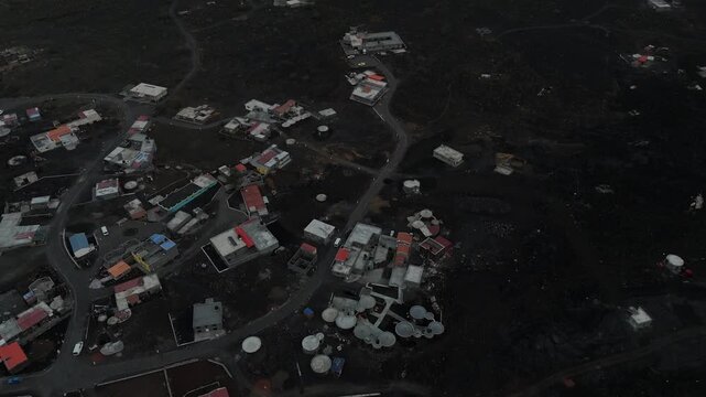 Aerial top down view of Portela village inside the Ch&atilde; das Caldeiras volcanic crater at Fogo Island, Cape Verde. Small houses built on dark volcanic lava soil in a unique lunar landscape