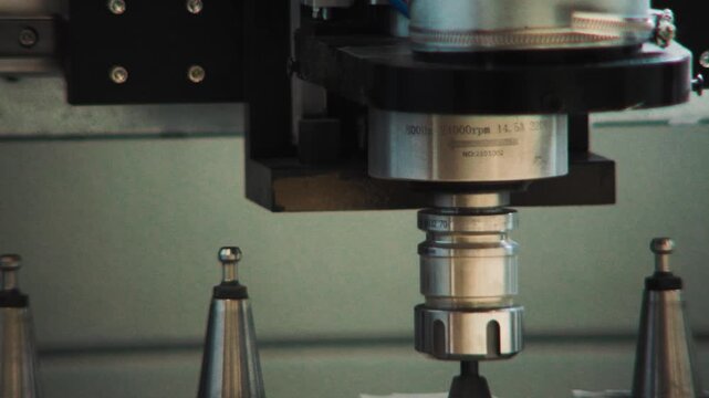 CNC spindle positioned above a row of tool holders during a tool change sequence.