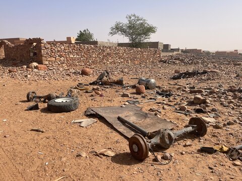Rusty car parts among historic desert buildings in Ouadane, Mauritania
