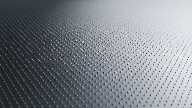 Countless tiny, regularly arranged conical dots of light and shadow on a reflective surface.