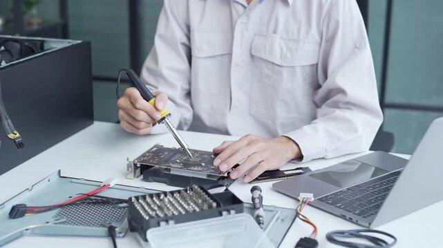 Computer engineer using a soldering iron fix graphic card