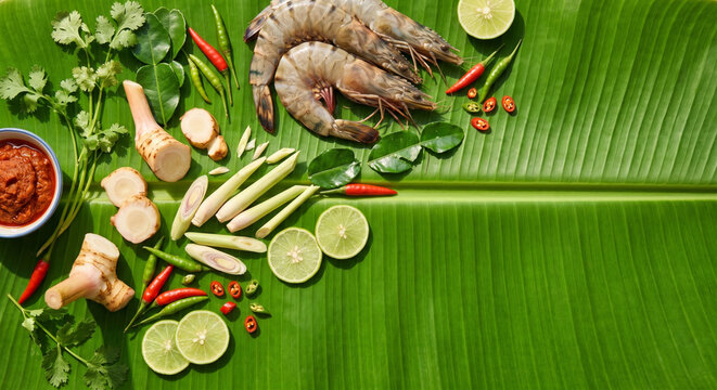 Overhead flat lay of Tom Yum Goong ingredients on fresh banana leaf, bottom right copy space