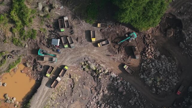 Aerial view of Tambang Pasir Merapi Kali Gendol Sand Mine with trucks and excavators in Kecamatan Cangkringan, Daerah Istimewa Yogya, Indonesia.