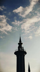 Obraz premium Silhouette Of Ornate Spire Tower Against Blue Sky With Soft Clouds At Sunset