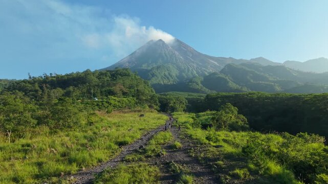 Aerial view of Bunker Kaliadem Merapi and the smoking peak of Mount Merapi surrounded by lush forests in Kecamatan Pakem, Daerah Istimewa Yogya, Indonesia.