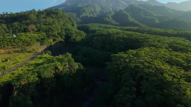 Aerial view of the deep green Ravine, Kali Gendol River, Mount Merapi and dense forest surrounding Bunker Kaliadem Merapi with people walking on a path Pakem, Yogyakarta, Indonesia.
