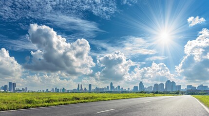 Obraz premium Expansive open road leading towards a modern city skyline under a bright, sunny sky with fluffy clouds