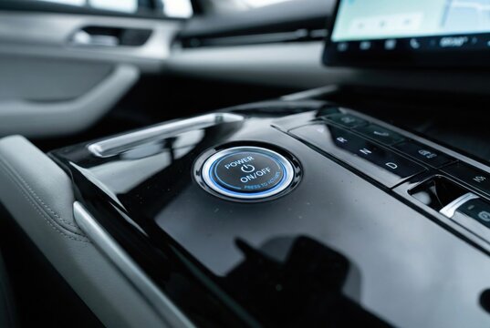 Macro view of futuristic electric car power on off button in black console
