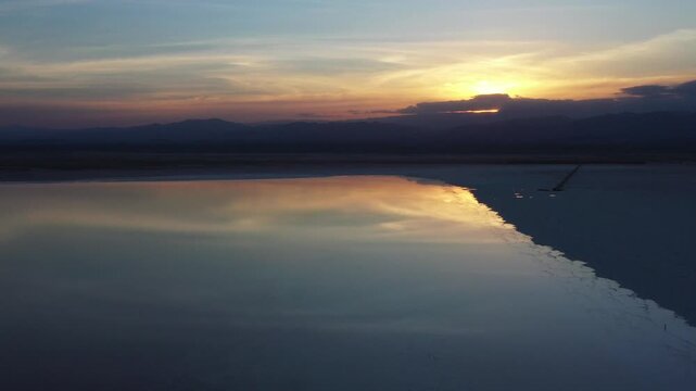 Aerial view of the Danakil Desert salt flats with the sun reflecting on the water surface and mountains at sunset Dalol, Afar, Ethiopia.