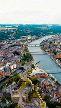 Vertical video. Namur, Belgium. Citadelle de Namur, one of Europe's largest fortresses, aerial panoramic view over the Meuse River and historic city center on a bright summer day. Drone footage. Rich