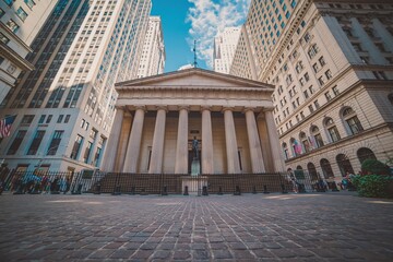 Fototapeta premium Imposing neoclassical architecture of a historic financial building with towering modern skyscrapers against a bright blue sky