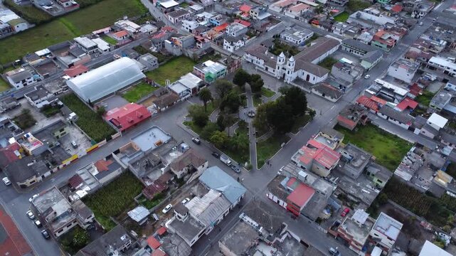 Drone advancing toward the Mitad del Mundo monument and church above Calacali central plaza in Ecuador
