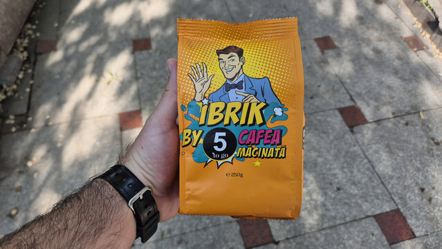 Cafea la ibrik 5 to Go. hand holding a bag of "Ibrik by 5 to go" ground coffee against a paved background. Picture taken on May 15, 2026 in Bucharest, Romania.