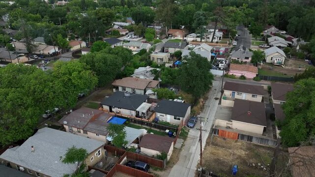 Residential neighborhood in Modesto, California with modest suburban homes and small backyards during flyover of working class community. Quiet and peaceful suburbia. Aerial drone flyover shot.