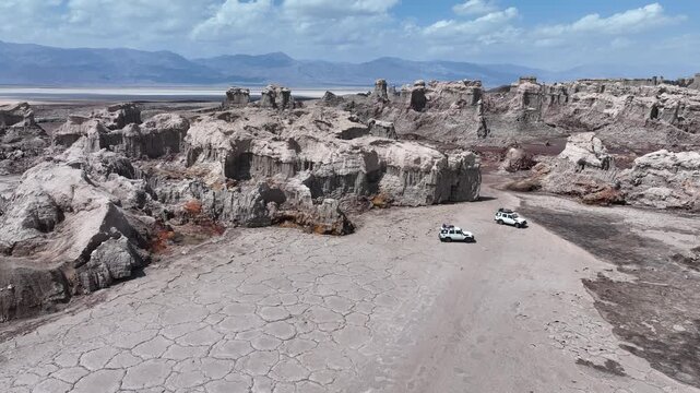 Aerial view of off-road vehicles parked near unique rock formations and cracked earth in the Danakil Desert Dalol, Afar, Ethiopia.