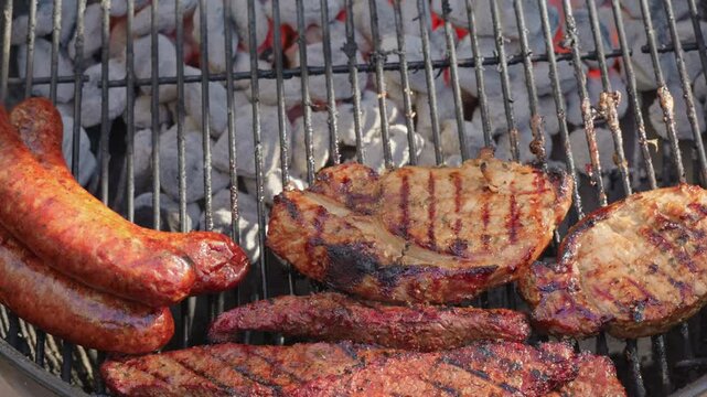 View of assorted meats cooking over hot charcoal briquettes