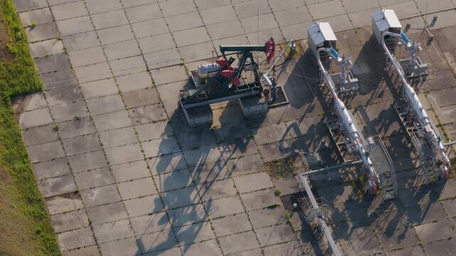Aerial view of an oil pump jack and industrial piping at the UGS Damborice facility on a concrete pad under bright sunlight in Damborice, South Moravian Region, Czechia.