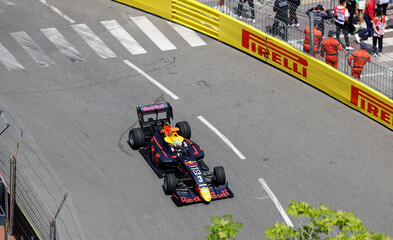 Fototapeta premium Monaco-Ville, Monaco on May 24, 2024. Overhead editorial view of an open-wheel Formula 1 racing car in classic Red Bull livery navigating a sharp corner on the historic Monte Carlo street circuit.