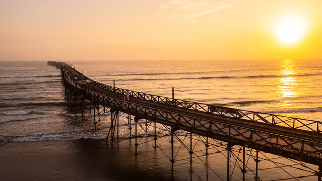 Golden sunset view of Pimentel Beach near Chiclayo on the northern coast of Peru. The image captures the warm evening light reflecting over the Pacific Ocean