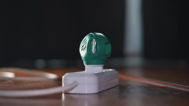 A hand plugs a mosquito repellent into an outlet. A close-up of the mosquito repellent with its electrical plug inside