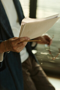 Vertical shot of anonymous author holding glasses and pages of printed novel
