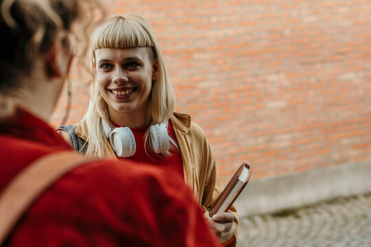 Female students smiling and talking, showing friendship outdoors