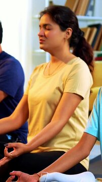Indian young family doing omkar meditation pranayama at home chanting aum breathing yoga together indoors during peaceful morning hours in a modern living room promoting yogic lifestyle