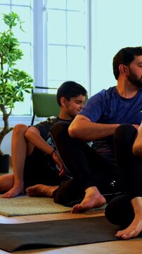 Indian family doing yog asana at home practicing ardha matsyendrasana seated spinal twist yoga together indoors during calm morning hours inside a modern lavish living space promoting health