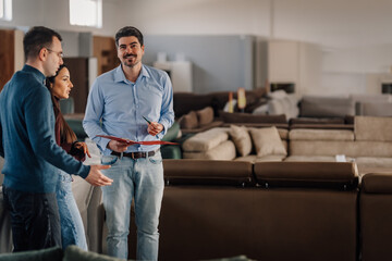 Fototapeta premium Salesman assisting couple choosing furniture in store