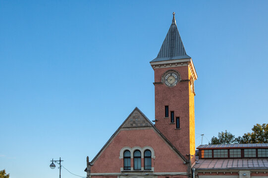 Sunlight bathes a red brick clock tower