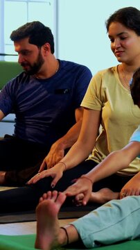 Indian family doing yog asana at home practicing janu shirasana seated head to knee yoga together indoors during calm morning hours inside a modern lavish living space promoting healthy lifestyle