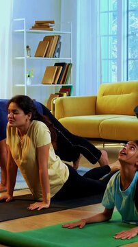 Indian family doing suryanamaskara at home practicing sun salutation yoga together indoors for healthy body and calm mind during morning routine inside a modern lavish living space