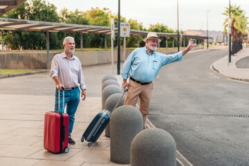 Two senior tourists with suitcases calling transportation outside the airport © Renata Hamuda