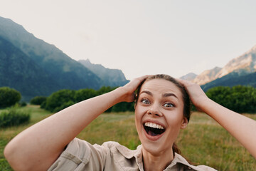 Fototapeta premium Cheerful woman outdoors, wide smile, hands on head, sunlight moment in a mountains valley, relaxed posture, vibrant natural colors, fresh air, happiness, lifestyle, nature, bright