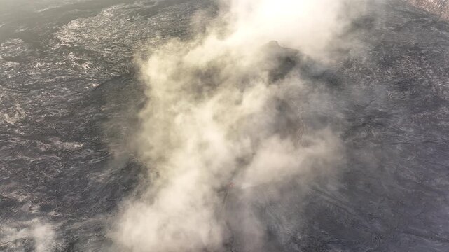Aerial view of the Danakil Desert volcanic crater with thick white smoke rising from the dark lava fields in Dalol, Afar, Ethiopia.